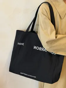 Minimalist black canvas tote bag detail view, featuring large capacity casual shoulder bag.