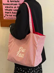 Detail der rot-weißen Canvas-Shopper-Tasche mit Buchstabenprint und großer Kapazität.