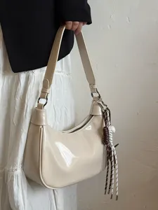 Stilvolle beige Lackleder Schulter-Unterarm-Tasche mit dekorativem Seil-Anhänger Detail.