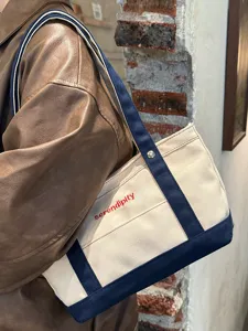 Λεπτομερής εικόνα της casual καμβά τσάντας tote με σχεδιασμό αντίθεσης και χερούλια.