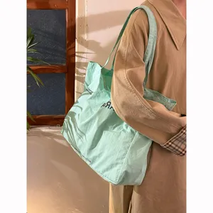 Casual light green canvas tote bag with letter print, large capacity, chic shoulder style.