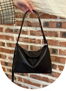 Detail shot of the minimalist black soft leather underarm shoulder bag, stylish commuter accessory.