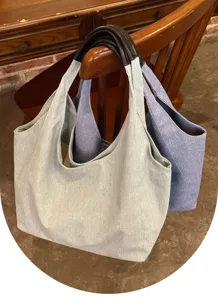 Detail view of casual denim tote bags hanging on a chair, showcasing large capacity design.