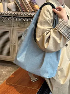 Detail view of the casual blue denim shoulder tote bag showcased in a cozy lifestyle setting.