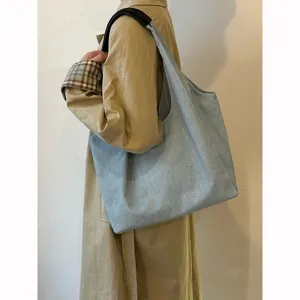 Casual light blue denim tote bag worn on shoulder, large capacity everyday commuter bag.