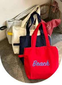 Detailansicht der Segeltuchtasche mit gesticktem Beach-Buchstaben und stabilem Tragegriff.
