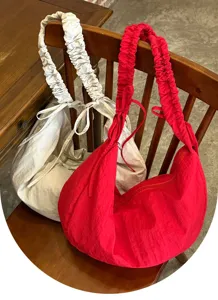 Detailed view of casual slouchy hobo bags with gathered straps in red and off-white colors.