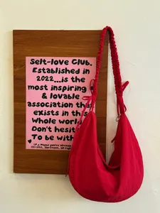 Red slouchy hobo bag detail showing the gathered scrunchie strap and soft fabric texture.