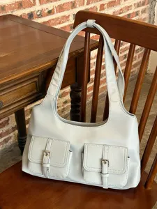 Detailed view of casual light blue shoulder bag with front utility pockets and metal buckles.