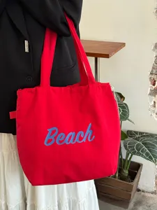 Rote Segeltuchtasche Detail mit blauen Beach Buchstaben und bequemem Schulterriemen.