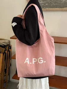 Λεπτομερής όψη της ροζ καμβά τσάντα ώμου tote με εκτύπωση γραμμάτων και υφή.