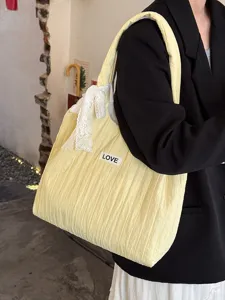 Detailansicht einer lässigen gelben plissierten Segeltuchtasche mit süßer weißer Schleife.