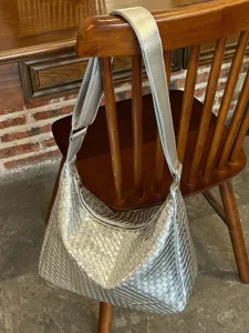 Detailansicht der silbernen geflochtenen Umhängetasche mit feiner Lederstruktur und breitem Gurt.