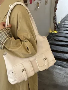Detail view of a chic minimalist shoulder bag featuring multiple functional front pockets.