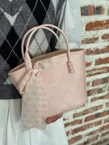 Vue détaillée du sac à main matelassé rose avec poignées élégantes et charme de foulard floral.
