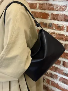 Minimalist black soft leather underarm shoulder bag, stylish commuter handbag detail view.