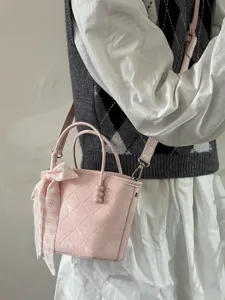 Détail de sac panier matelassé rose avec foulard élégant et perle pour style doux quotidien.