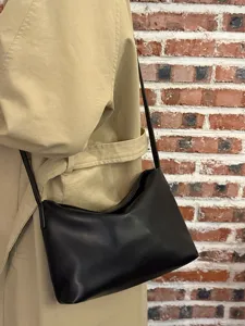 Minimalist black soft leather underarm shoulder bag detail view with trench coat look
