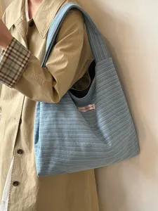 Close-up detail of the light blue striped canvas tote bag showing texture and sewn tag.