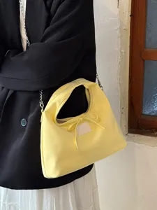 Λεπτομερής λήψη της κίτρινης τσάντας με φιόγκο, αλυσίδα και κομψό σχεδιασμό.