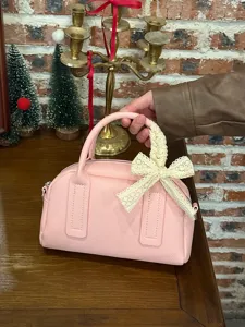 Close-up detail of the pink boston pillow bag featuring an elegant lace bow decoration.