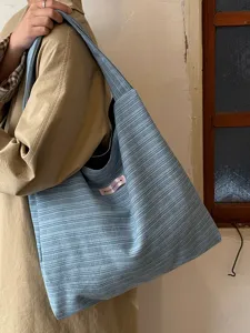 Light blue striped canvas shoulder tote bag detail shot, casual daily commuter bag.