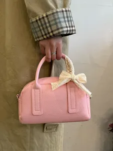 Close-up of pink Boston handbag with lace bow handle detail, stylish and elegant daily use.