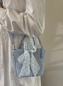 Sac à main seau matelassé bleu clair avec joli nœud floral doux, vue de détail.