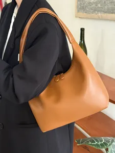 Detailed view of brown soft leather shoulder bag worn by model, minimalist style.
