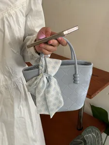 Gros plan détaillé sur le sac à main matelassé bleu clair avec un joli ruban floral élégant.