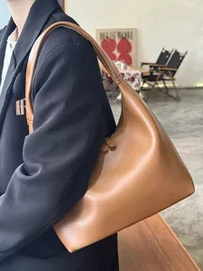 Detailed view of the brown soft leather shoulder bag, minimalist hobo style with elegant drape.