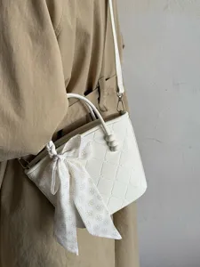 Vue rapprochée et détaillée d'un sac bandoulière blanc élégant avec nœud et perles.