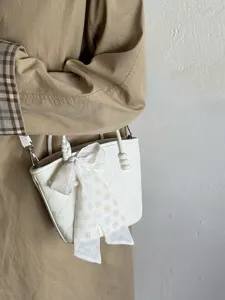Vue détaillée d'un sac seau matelassé blanc élégant avec foulard floral et breloque en perles.
