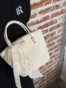 Sac à main seau blanc crème chic avec élégante écharpe nœud et détails perlés poignée.