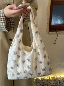 Detalle del bolso de hombro de lona bordado con flores violetas de estilo vintage.