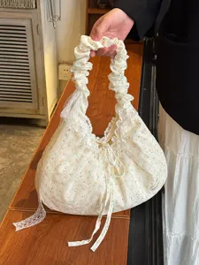 Primer plano de bolso de lona floral con ribete de encaje, asa con volantes y lazo.