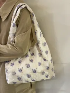 Detalle de bolso de lona con estampado floral retro y morado, con correa ancha para uso diario.