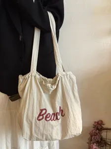 Nahaufnahme der lässigen Canvas-Einkaufstasche in Beigefarbe mit modischem Beach-Buchstaben-Druck.