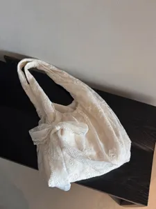 Detailed view of the elegant cream white lace tote bag with bow accent and comfy shoulder strap.