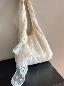 Detailed view of off-white lace shoulder bag showing floral texture and bow strap.