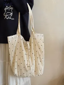 Close-up of white chiffon tote bag with black floral pattern, textured fabric and straps.