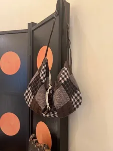 Detail view of a retro patchwork plaid canvas shoulder bag with slouchy design and unique strap.