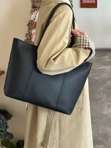 Detailed shot of a stylish black PU leather tote bag worn on shoulder for daily commute.