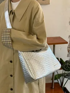 Detailaufnahme einer stylischen silbernen geflochtenen Umhängetasche zum Trenchcoat.