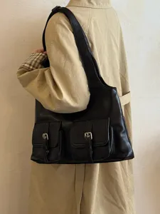 Detail view of the black PU leather shoulder bag featuring dual front pockets and metal buckles.