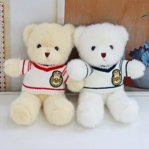Detailed shot of cute plush teddy bears wearing knit sweaters with anchor badges, soft toy.