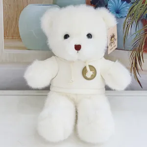 White plush teddy bear toy detailed shot, wearing a cute beige hoodie with letter badge.