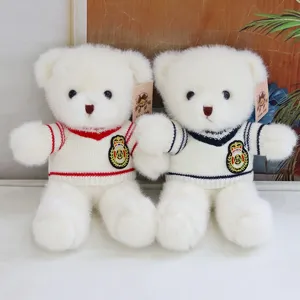 Detailed shot of two cute white teddy bears in red and blue striped knitted sweaters with crests.