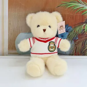 Detailed close-up shot of a cute cream teddy bear wearing a striped sweater with anchor badge.