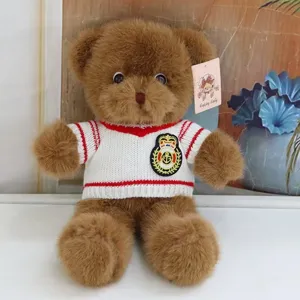Cute brown plush teddy bear toy wearing a white knitted sweater with red stripes for kids gift.